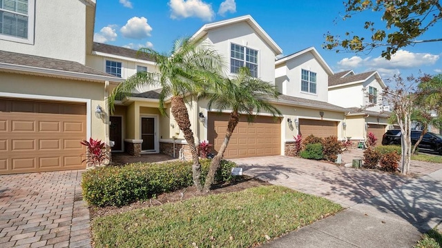 view of property featuring a garage, decorative driveway, and stucco siding