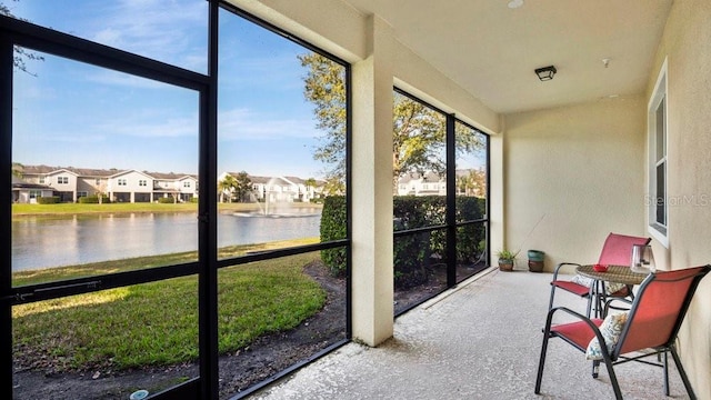 sunroom featuring a water view and a residential view