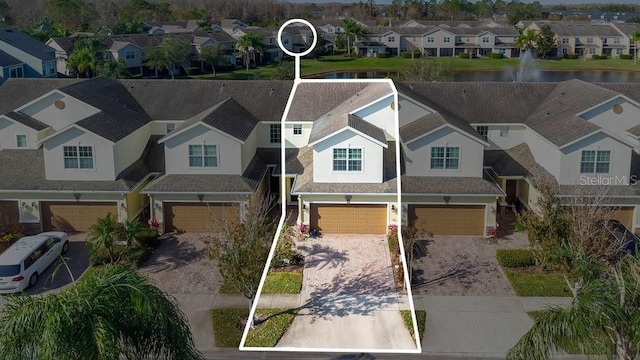 exterior space with a garage, driveway, a residential view, and stucco siding