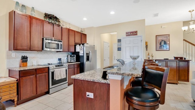 kitchen featuring appliances with stainless steel finishes, a breakfast bar area, backsplash, and visible vents