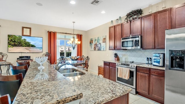 kitchen with visible vents, backsplash, appliances with stainless steel finishes, a sink, and a chandelier