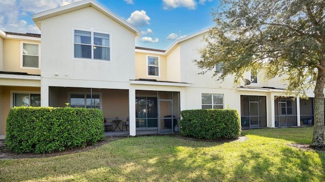 back of property featuring a lawn, a sunroom, and stucco siding