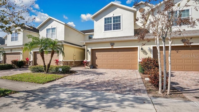 traditional-style home with a garage, decorative driveway, and stucco siding