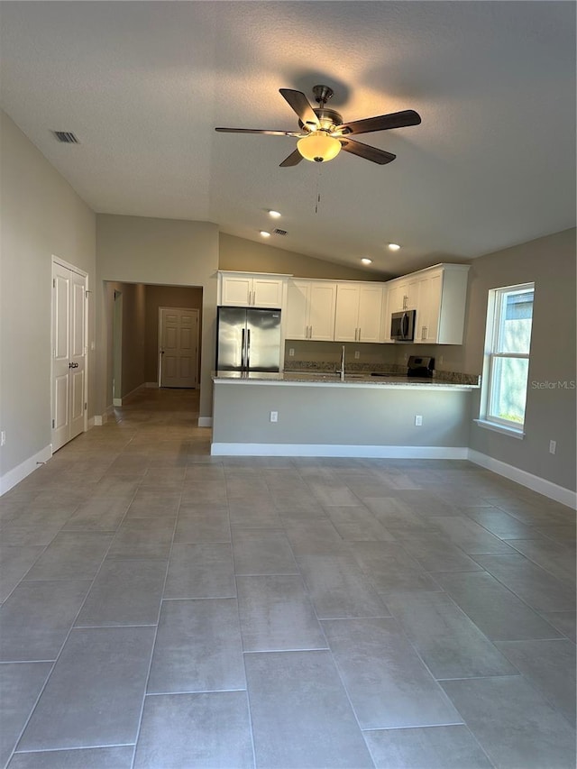 kitchen with lofted ceiling, ceiling fan, stainless steel appliances, white cabinets, and kitchen peninsula