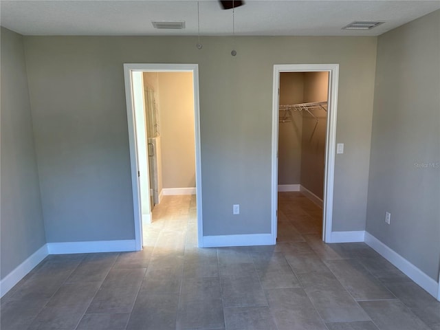 unfurnished bedroom featuring a walk in closet and a closet