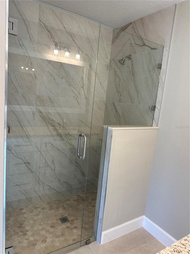 bathroom with a textured ceiling and a shower with shower door