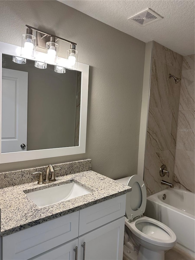 full bathroom with tiled shower / bath, vanity, a textured ceiling, and toilet