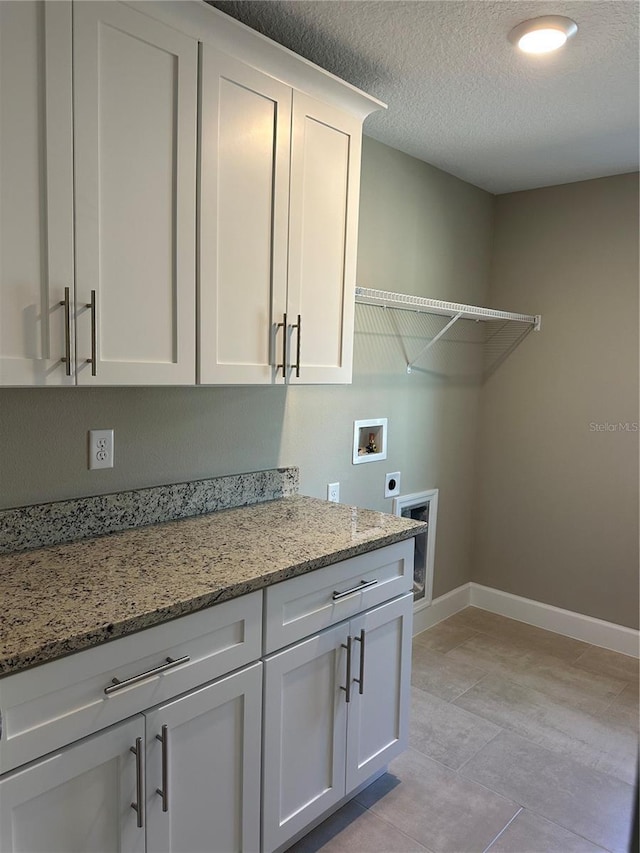 laundry area featuring cabinets, hookup for an electric dryer, hookup for a washing machine, and a textured ceiling