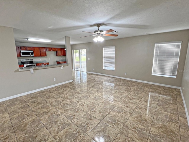 kitchen with kitchen peninsula, a textured ceiling, stainless steel appliances, and ceiling fan