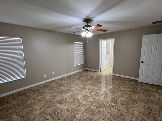 empty room with ceiling fan and a textured ceiling