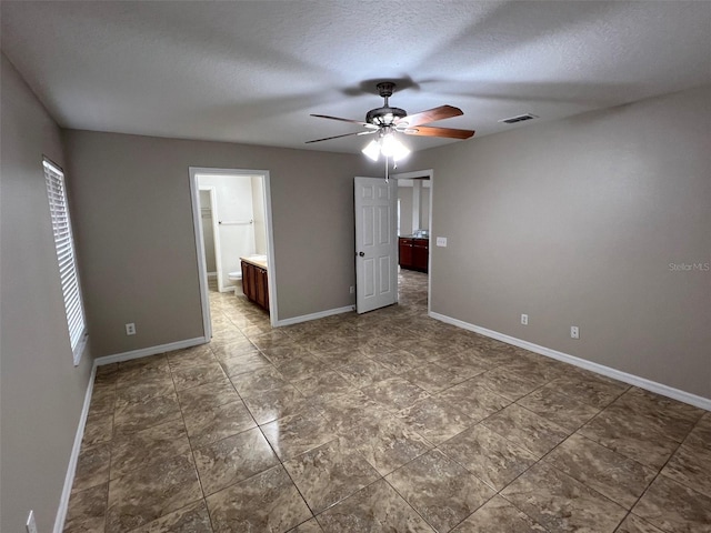 empty room with ceiling fan and a textured ceiling