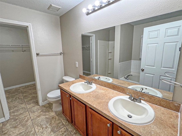 bathroom featuring a washtub, a textured ceiling, vanity, and toilet