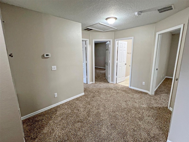 interior space with a textured ceiling and light carpet