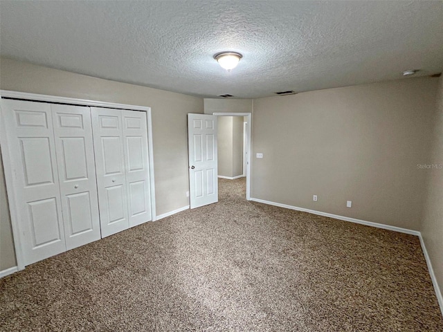 unfurnished bedroom with a textured ceiling, carpet floors, and a closet