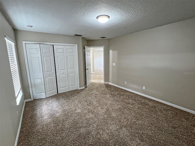 unfurnished bedroom featuring carpet flooring, a textured ceiling, multiple windows, and a closet