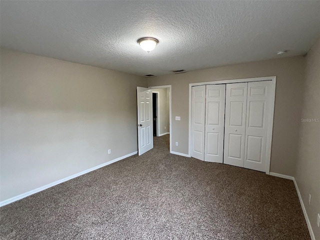 unfurnished bedroom with dark carpet, a textured ceiling, and a closet