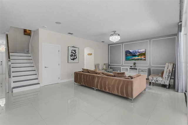 living room with light tile patterned floors, a textured ceiling, and an inviting chandelier