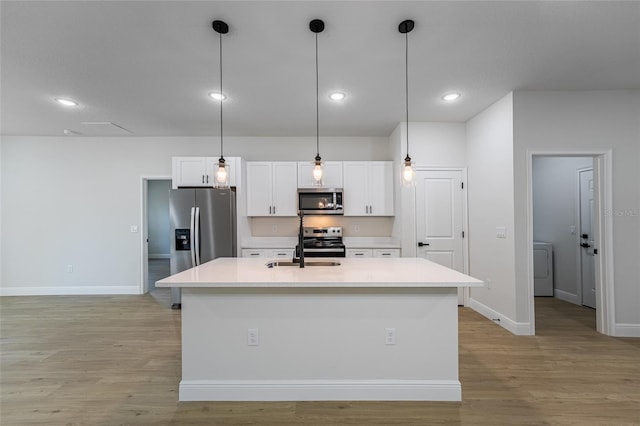 kitchen with light wood-style floors, a kitchen island with sink, white cabinetry, and stainless steel appliances