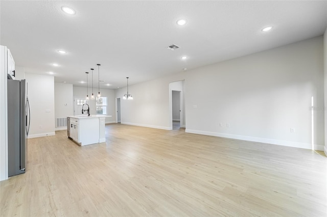 unfurnished living room featuring light wood finished floors, a sink, visible vents, and recessed lighting