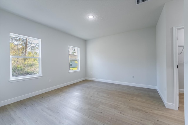 unfurnished bedroom with light wood-type flooring, multiple windows, and baseboards