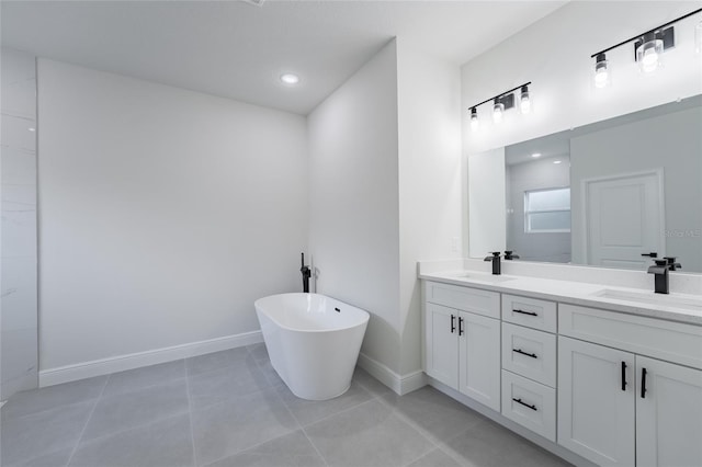 full bath with a freestanding bath, double vanity, a sink, and baseboards