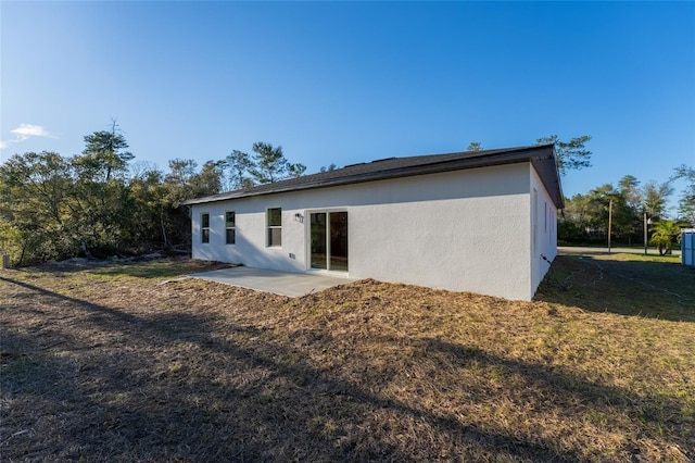 back of property featuring a lawn, a patio area, and stucco siding