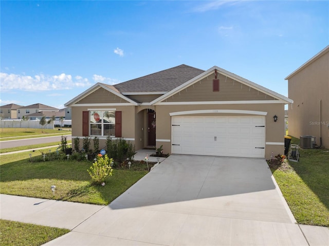 view of front of property with central AC, a front yard, and a garage