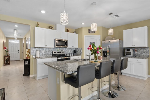 kitchen featuring appliances with stainless steel finishes, sink, pendant lighting, white cabinetry, and an island with sink