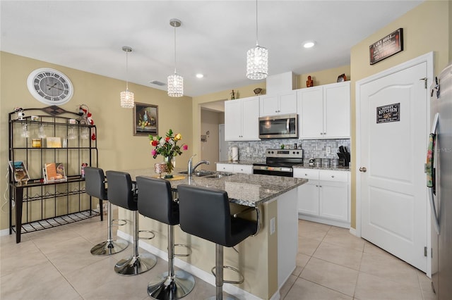 kitchen with appliances with stainless steel finishes, sink, pendant lighting, a center island with sink, and white cabinets