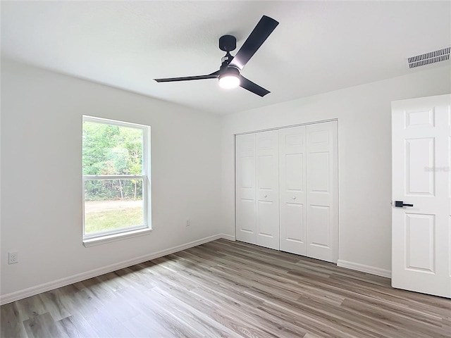 unfurnished bedroom featuring light wood-type flooring, ceiling fan, and a closet