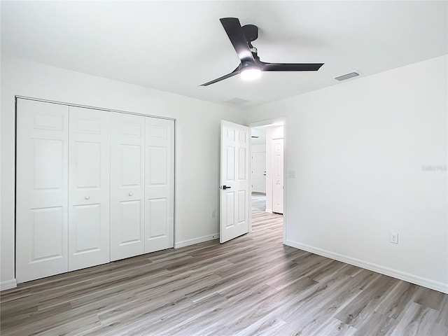 unfurnished bedroom featuring ceiling fan, light hardwood / wood-style flooring, and a closet