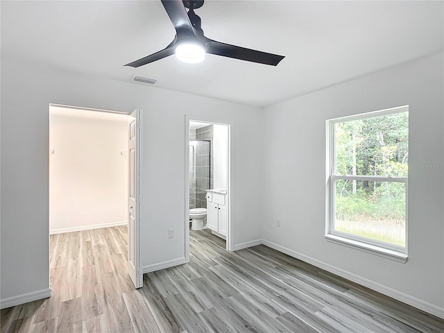 unfurnished bedroom featuring ensuite bathroom, ceiling fan, and light hardwood / wood-style flooring