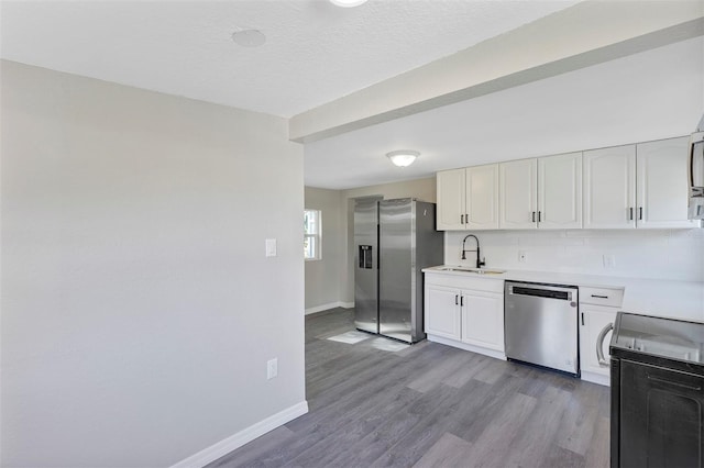 kitchen with white cabinetry, sink, stainless steel appliances, backsplash, and light hardwood / wood-style floors