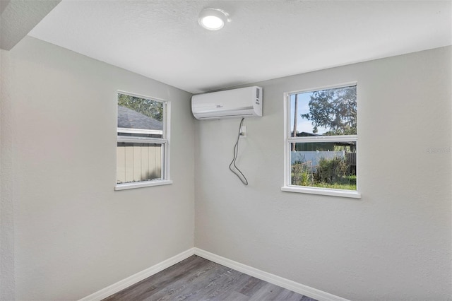 unfurnished room featuring a wall mounted AC and hardwood / wood-style floors