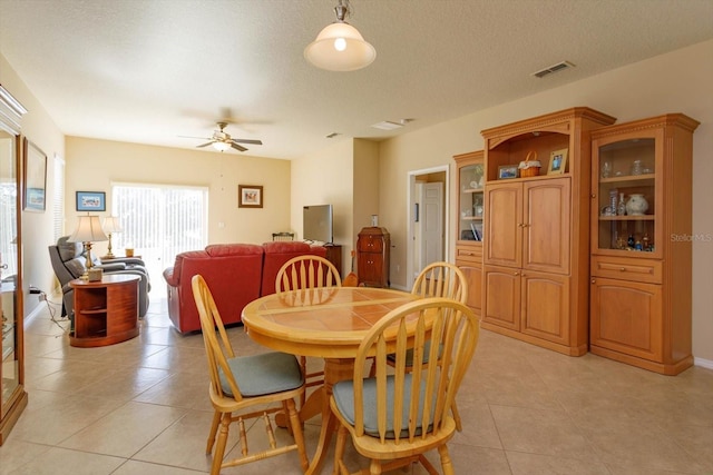 tiled dining area with a textured ceiling and ceiling fan