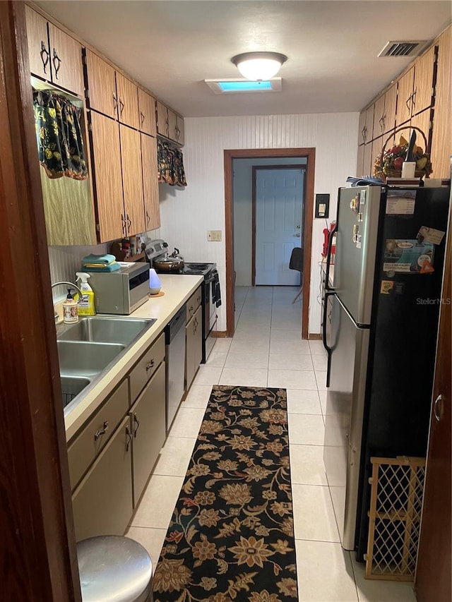 kitchen with appliances with stainless steel finishes, sink, wood walls, and light tile patterned flooring