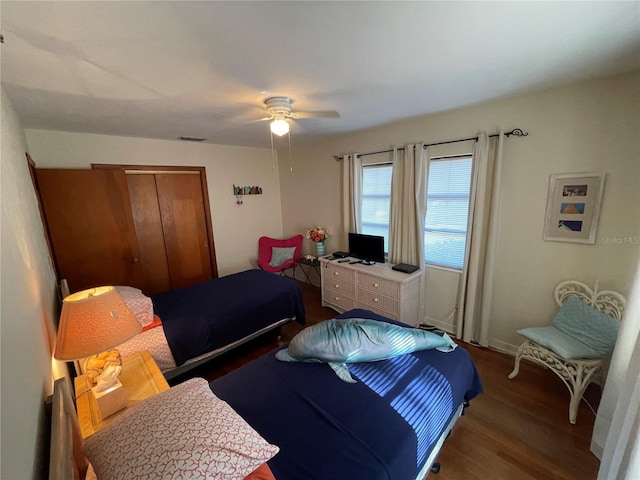 bedroom with dark hardwood / wood-style flooring, a closet, and ceiling fan