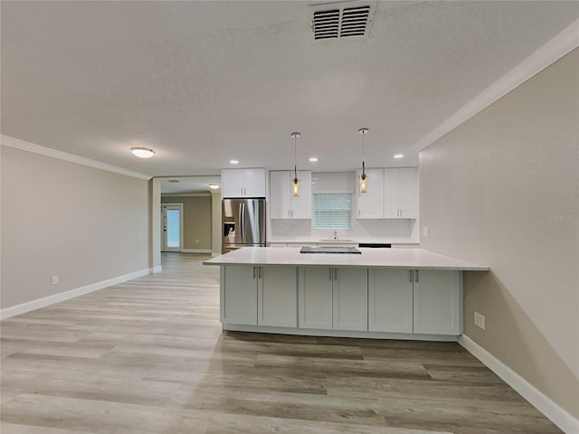 kitchen featuring stainless steel fridge, ornamental molding, decorative light fixtures, light hardwood / wood-style flooring, and white cabinets