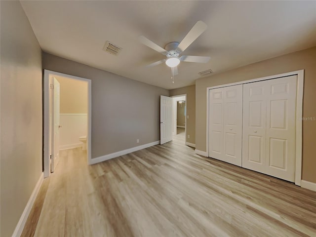 unfurnished bedroom featuring ceiling fan, light hardwood / wood-style floors, ensuite bathroom, and a closet