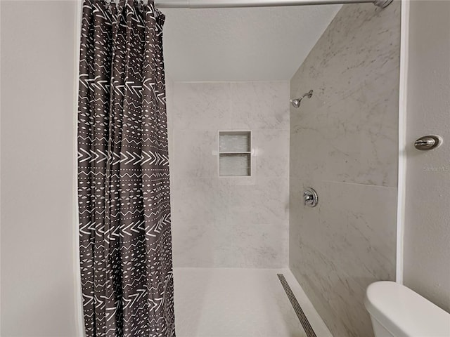 bathroom featuring tiled shower and toilet