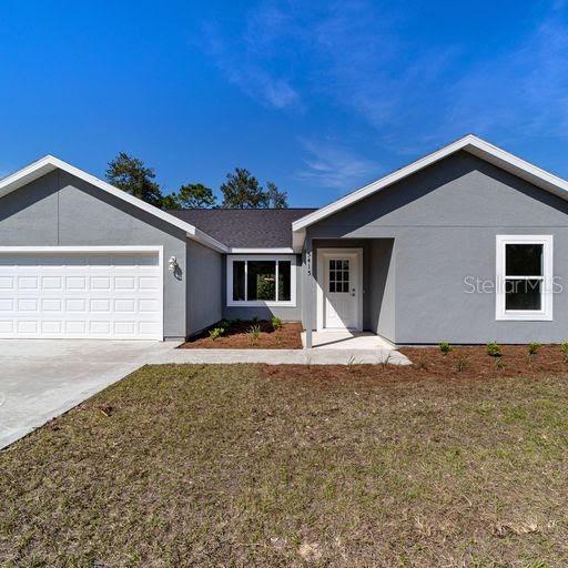 ranch-style house featuring a garage and a front lawn