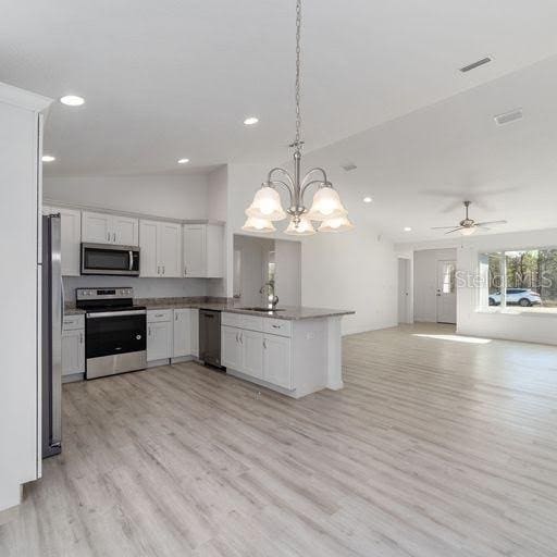 kitchen featuring white cabinets, ceiling fan with notable chandelier, decorative light fixtures, kitchen peninsula, and stainless steel appliances