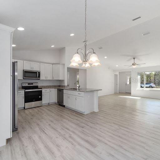 kitchen featuring kitchen peninsula, ceiling fan with notable chandelier, stainless steel appliances, decorative light fixtures, and white cabinets