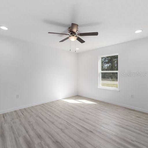 empty room with light wood-type flooring and ceiling fan