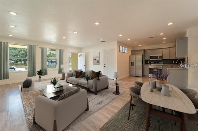 living area featuring recessed lighting, baseboards, and light wood finished floors