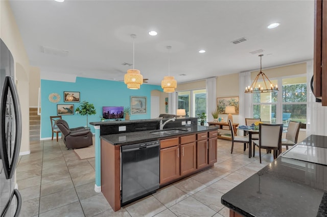 kitchen featuring sink, decorative light fixtures, dark stone countertops, stainless steel fridge, and dishwasher