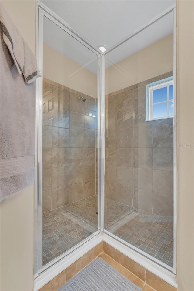 bathroom with an enclosed shower and tile patterned floors