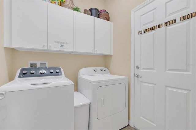 clothes washing area featuring independent washer and dryer and cabinets