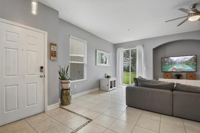 tiled living room with ceiling fan and a textured ceiling