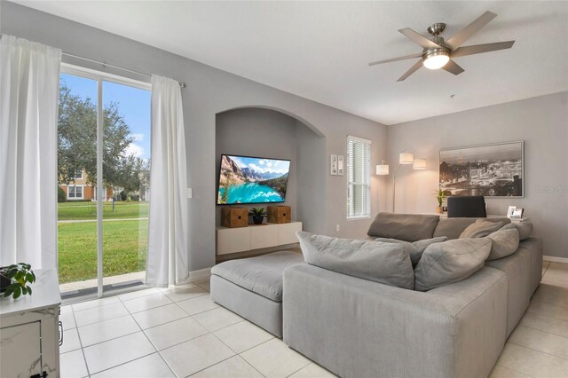 tiled living room with a wealth of natural light and ceiling fan